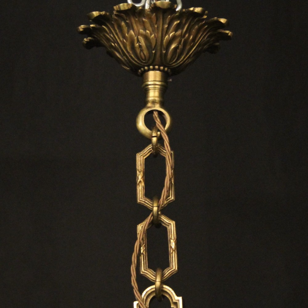 A French gilt bronze six-light chandelier featuring a central fluted stem, scrolled arms with white candle sleeves, and a geometric suspension chain. View X