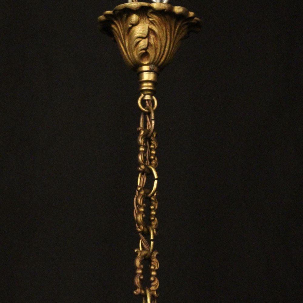 An antique French gilded bronze hall lantern featuring a cylindrical glass shade, three central candle sleeves, and ornate cast scrollwork mounts suspended from a chain. View X