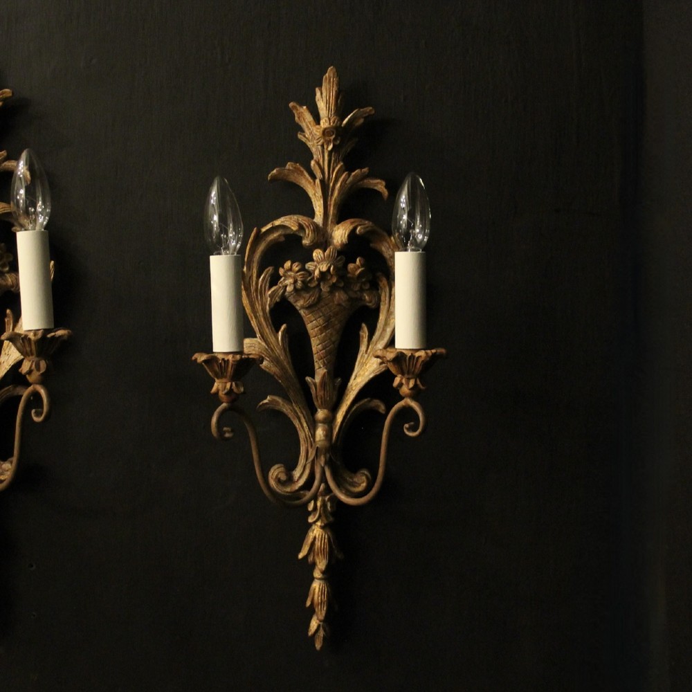 A pair of French carved wooden two-arm wall sconces featuring ornate floral basket motifs, acanthus leaf scrollwork, and white candle sleeves. View II