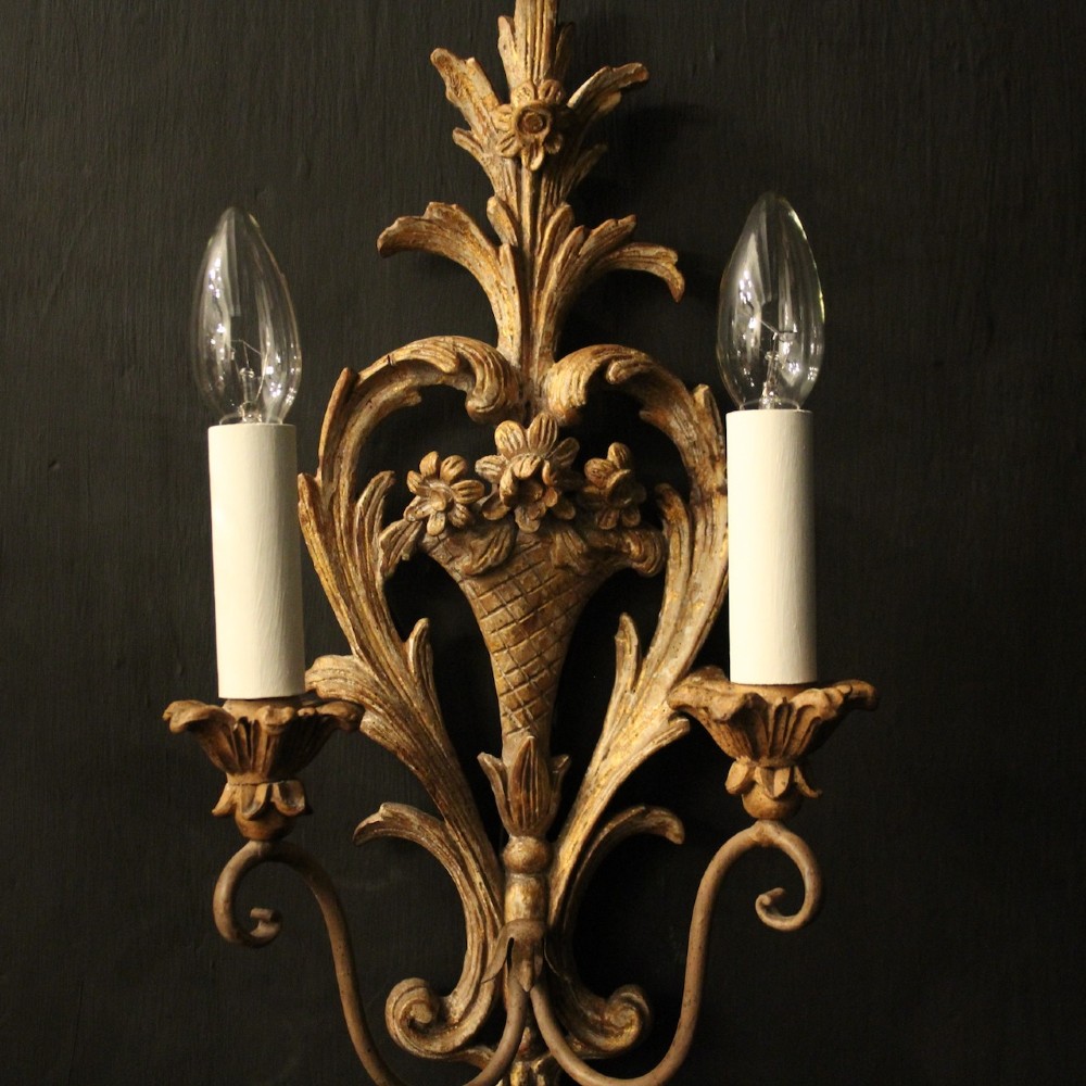 A pair of French carved wooden two-arm wall sconces featuring ornate floral basket motifs, acanthus leaf scrollwork, and white candle sleeves. View IV