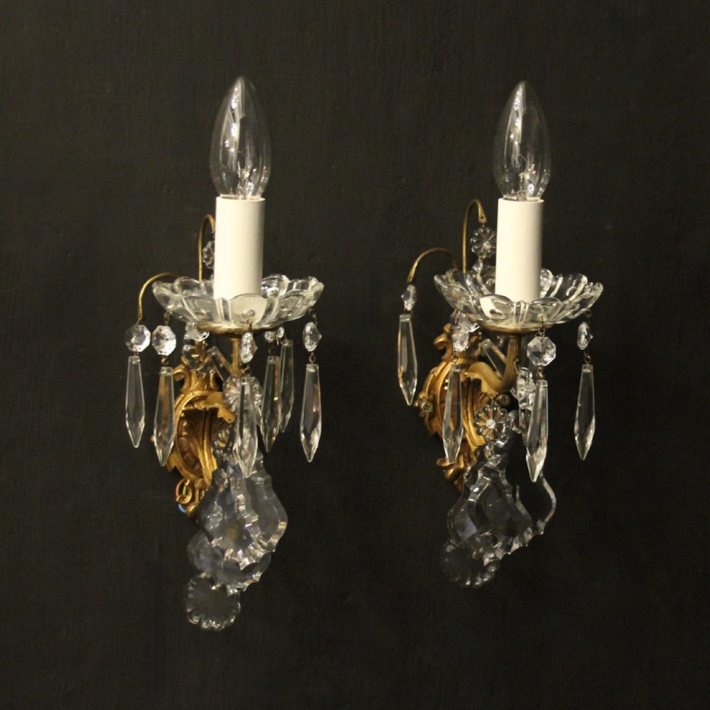 A pair of French gilded single-arm wall lights featuring clear crystal drops and scalloped glass drip pans.