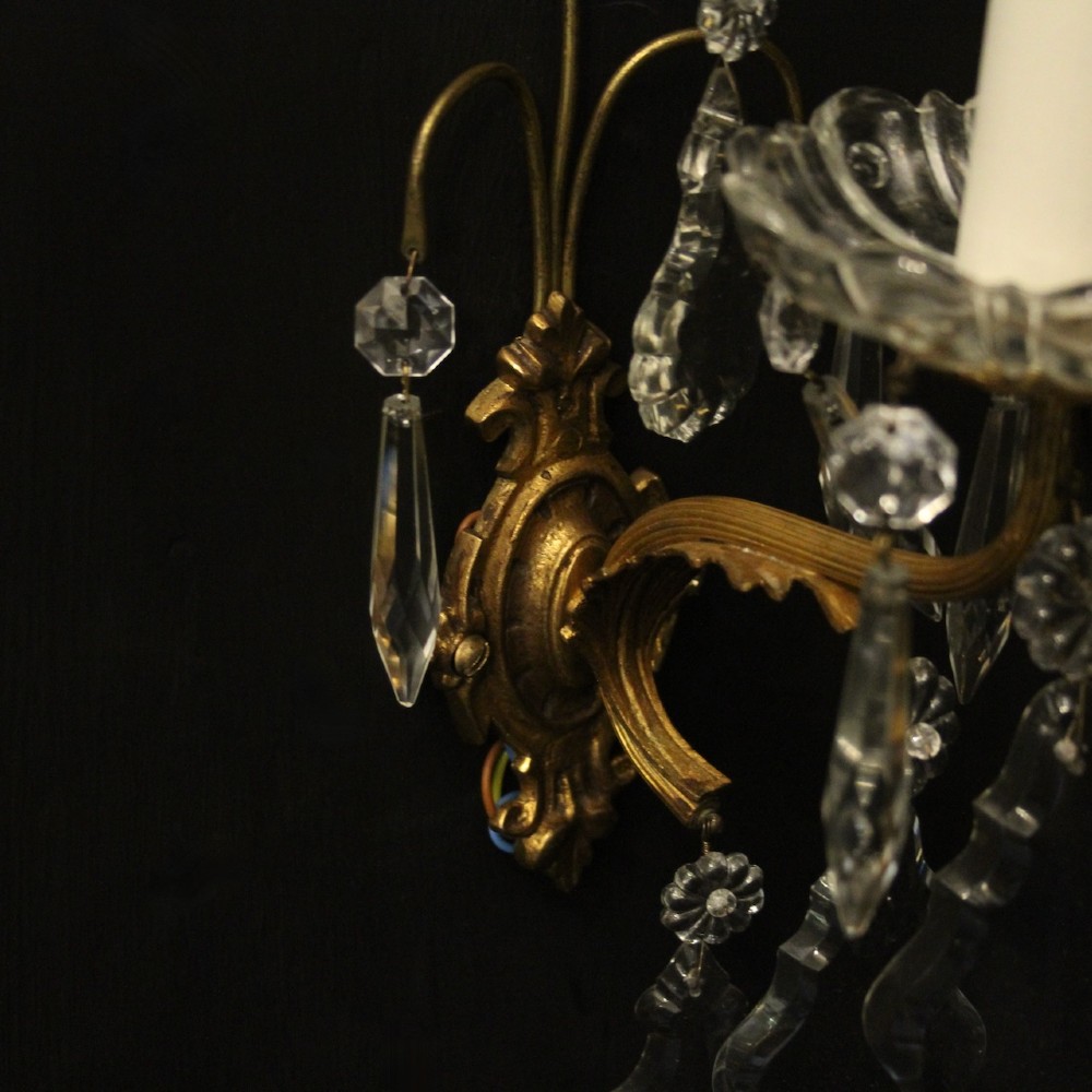 A pair of French gilded single-arm wall lights featuring clear crystal drops and scalloped glass drip pans. View VII
