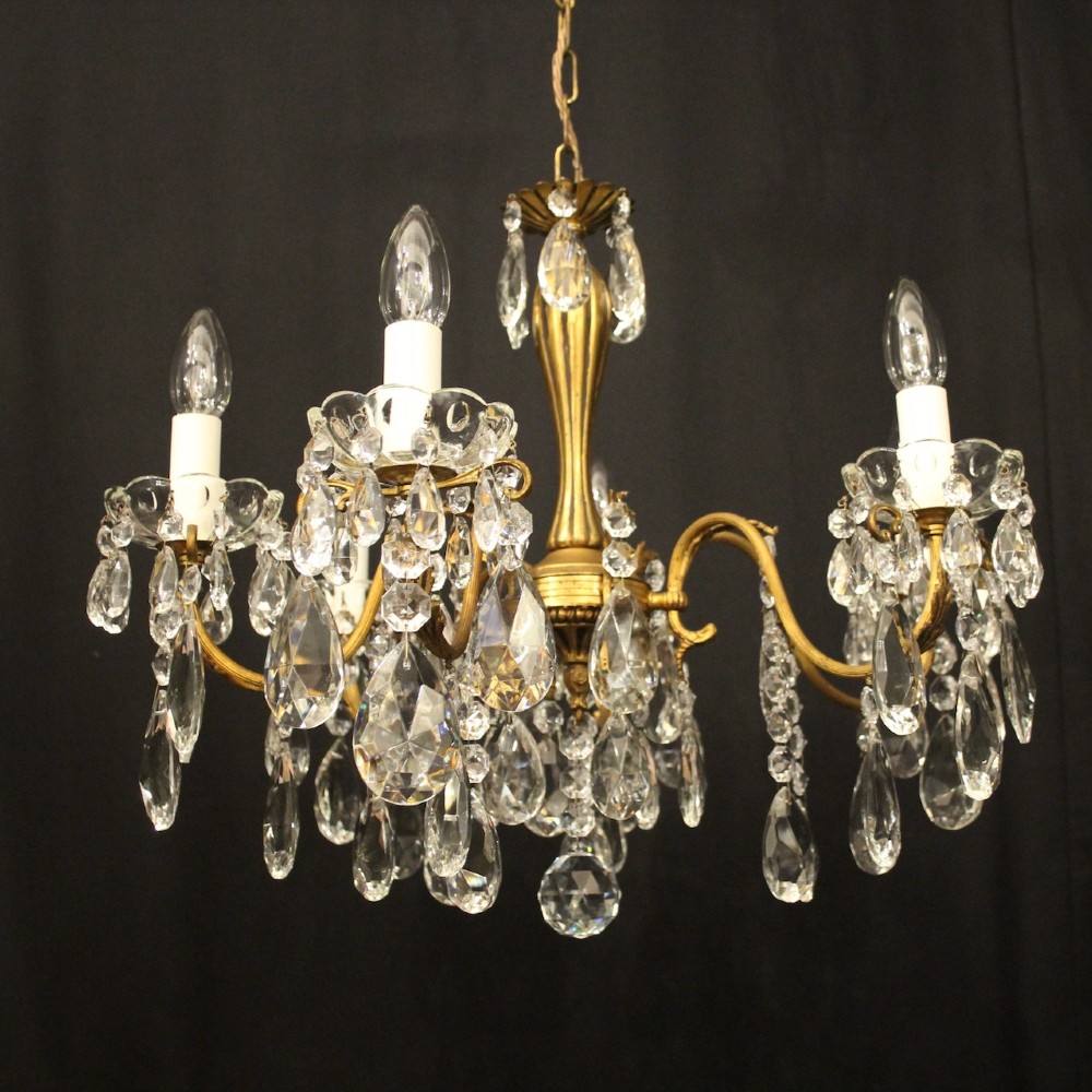 A French gilded brass five-arm chandelier decorated with hanging crystal teardrops and white candle sleeves. View II