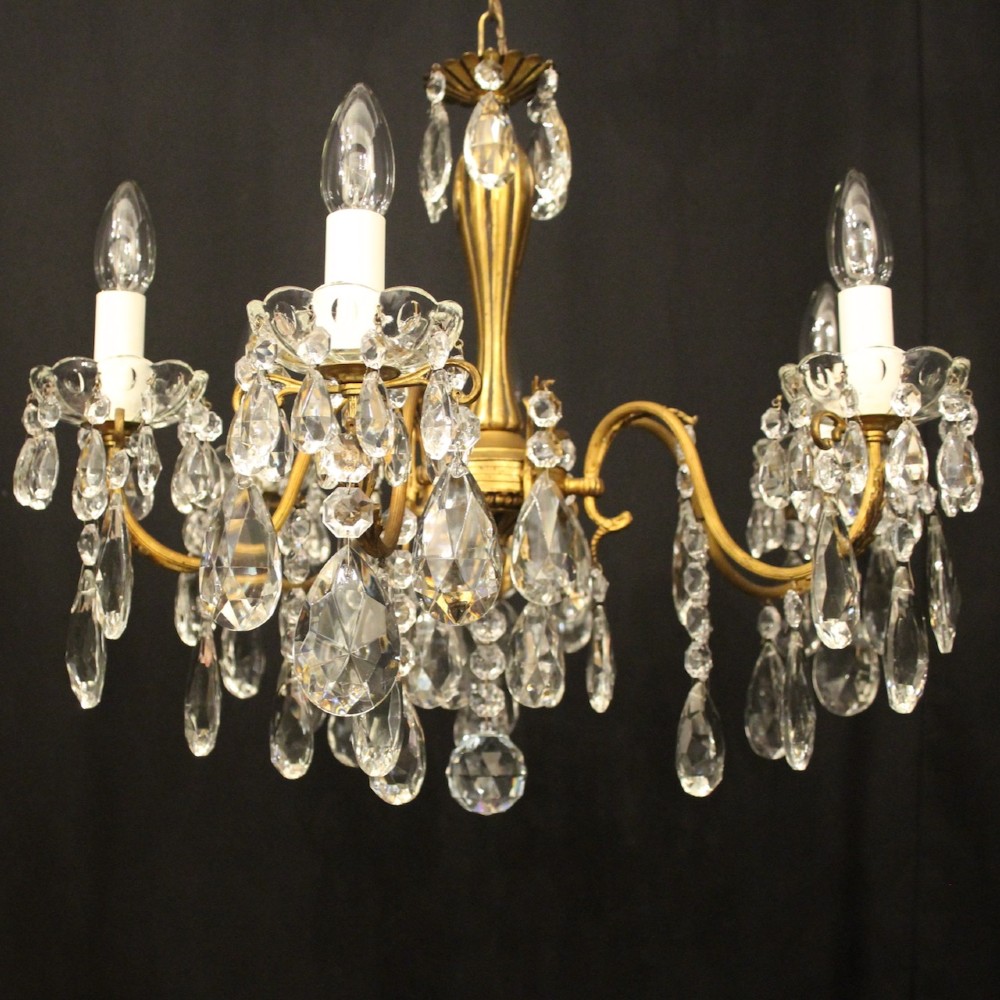 A French gilded brass five-arm chandelier decorated with hanging crystal teardrops and white candle sleeves. View III