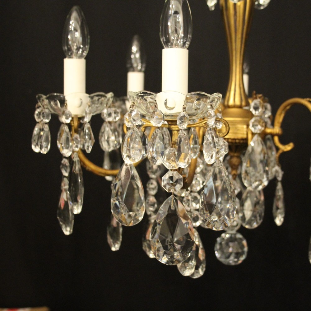 A French gilded brass five-arm chandelier decorated with hanging crystal teardrops and white candle sleeves. View IV