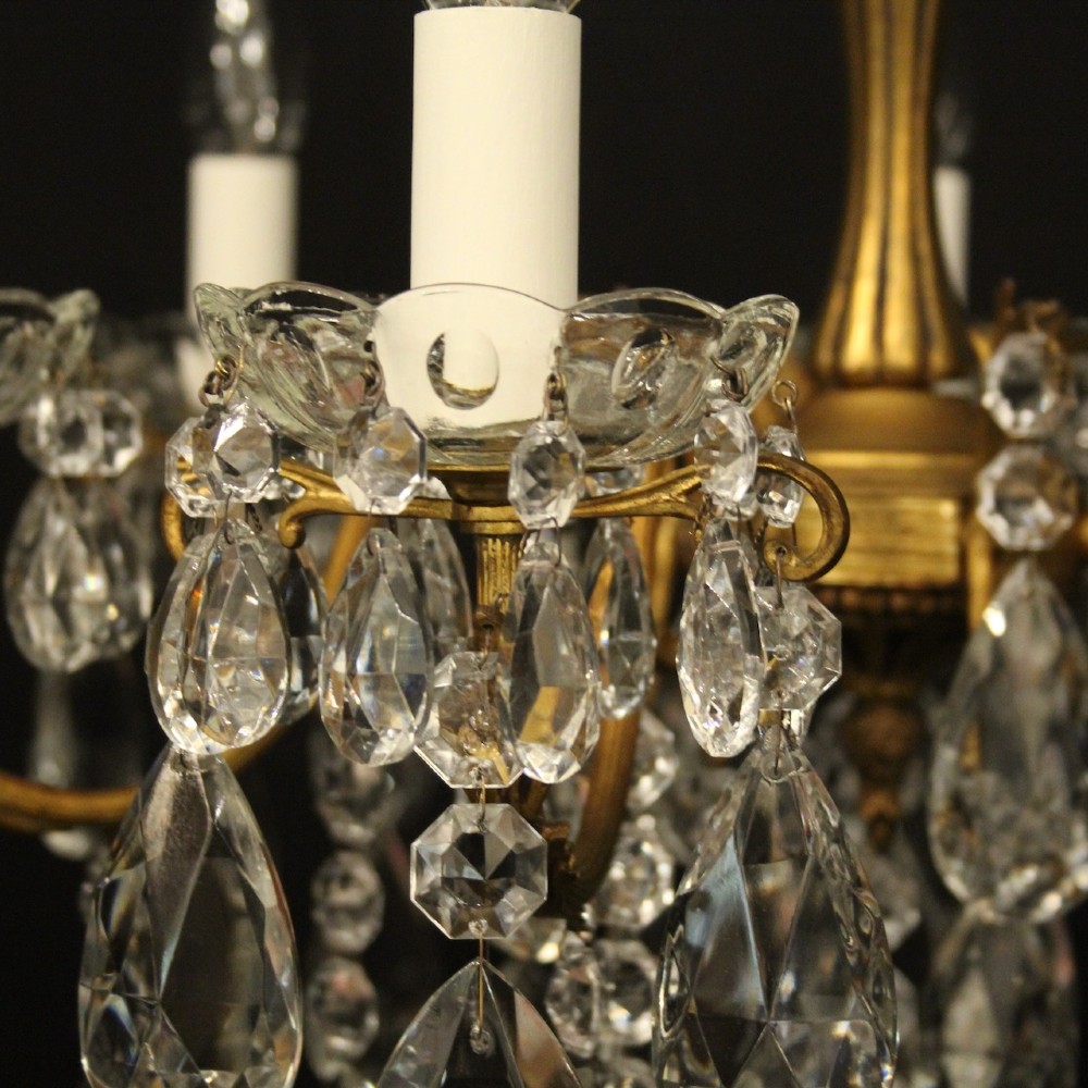 A French gilded brass five-arm chandelier decorated with hanging crystal teardrops and white candle sleeves. View V