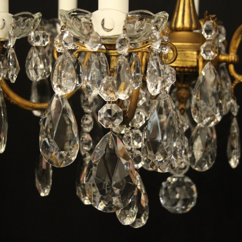 A French gilded brass five-arm chandelier decorated with hanging crystal teardrops and white candle sleeves. View VI