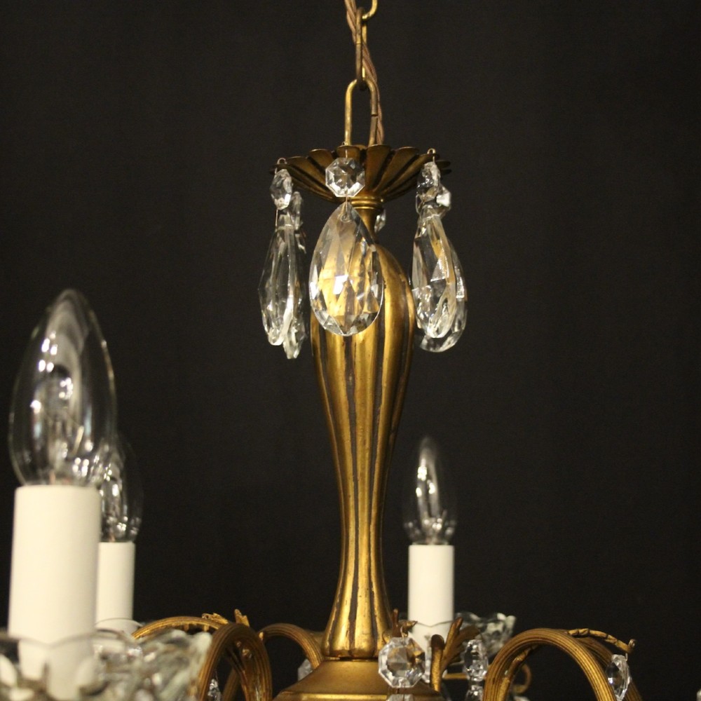 A French gilded brass five-arm chandelier decorated with hanging crystal teardrops and white candle sleeves. View IX