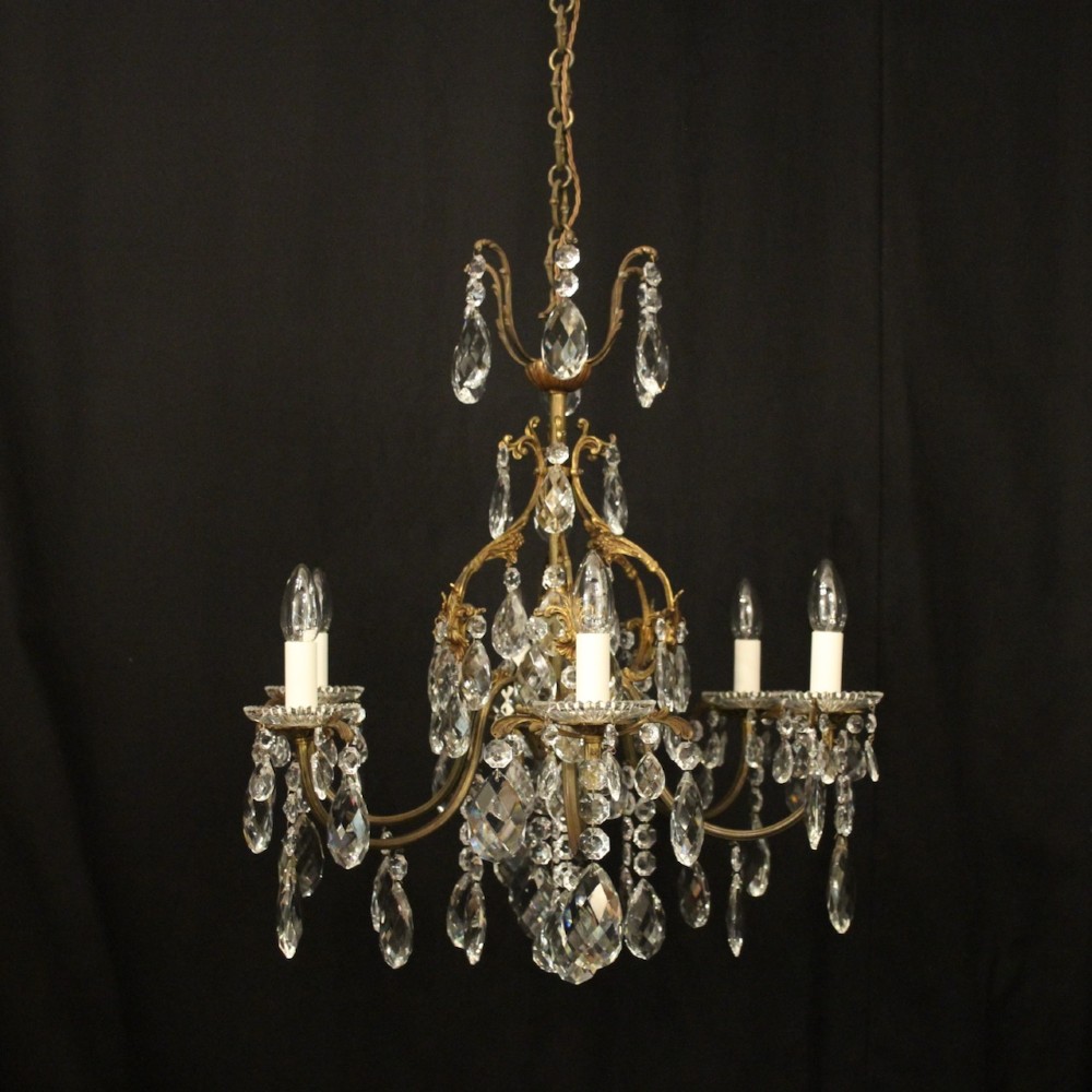 An antique French six-arm crystal chandelier featuring a gilt metal cage frame suspended with faceted glass drops and glass drip pans.