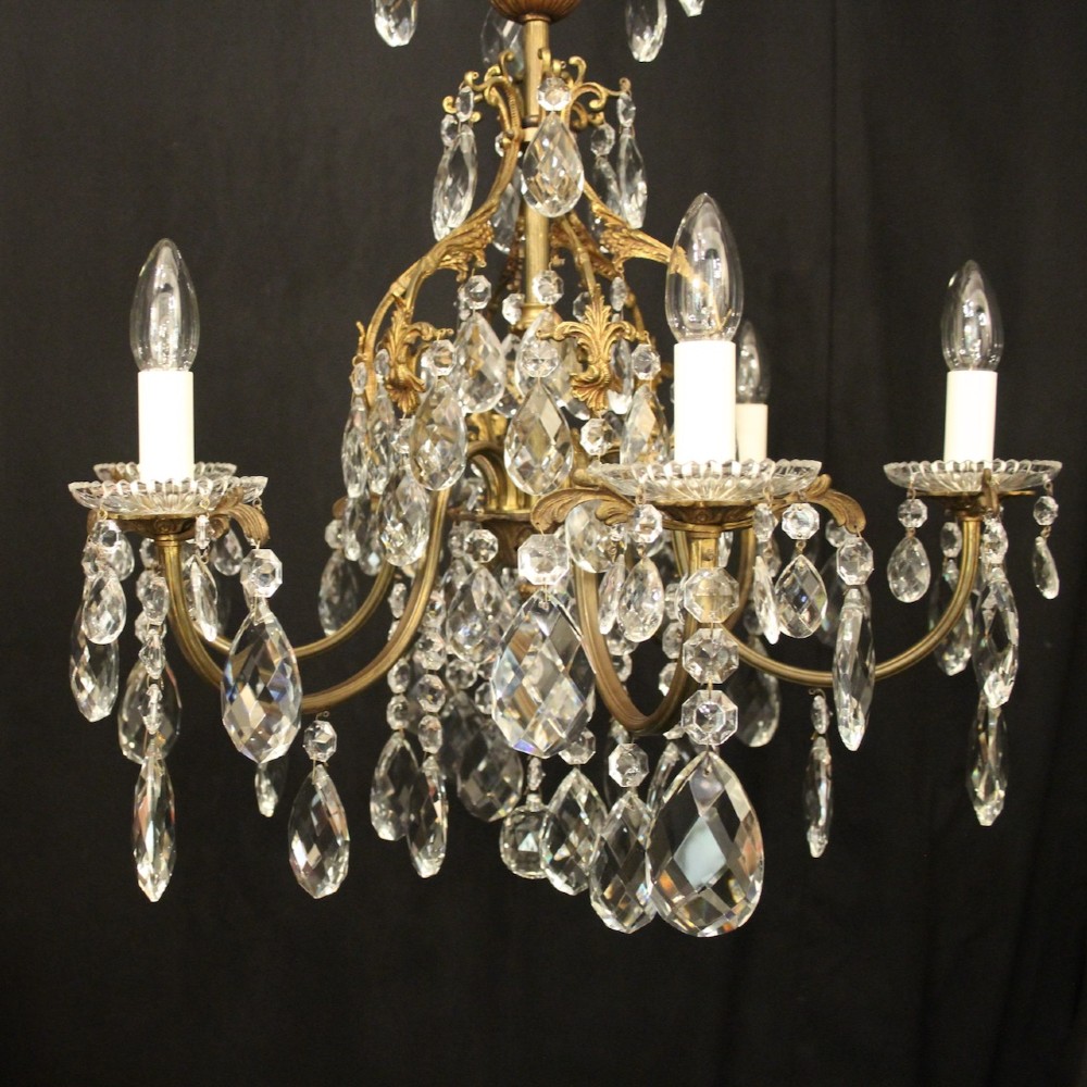 An antique French six-arm crystal chandelier featuring a gilt metal cage frame suspended with faceted glass drops and glass drip pans. View II