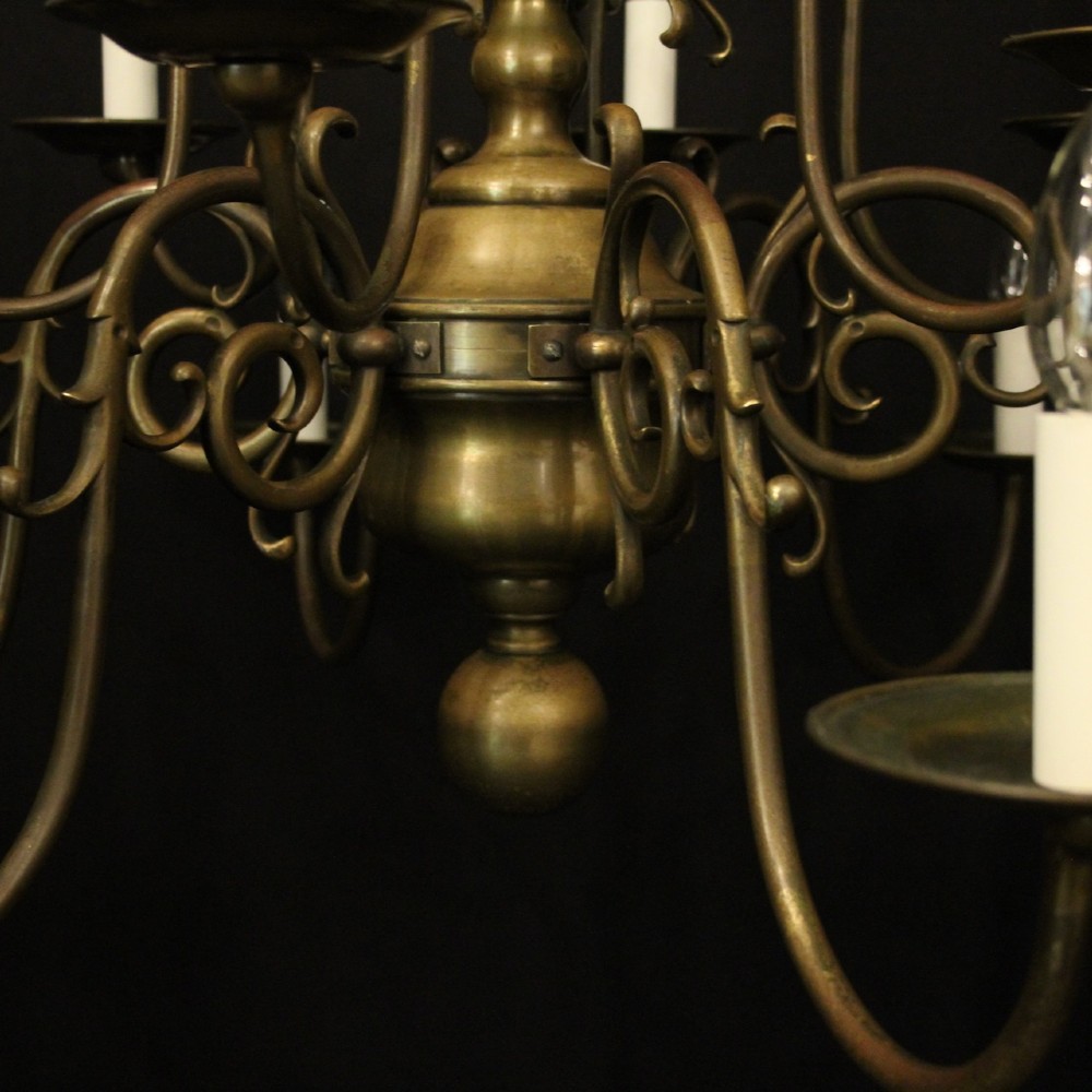 An antique English twelve-light bronze chandelier featuring scrollwork arms, candle sleeves, drip pans, and a turned central stem. View IV