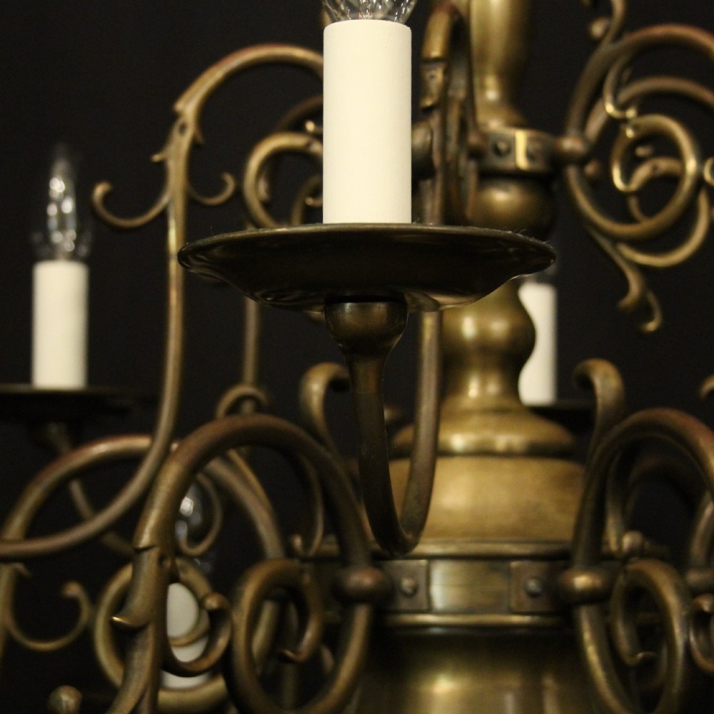 An antique English twelve-light bronze chandelier featuring scrollwork arms, candle sleeves, drip pans, and a turned central stem. View VI