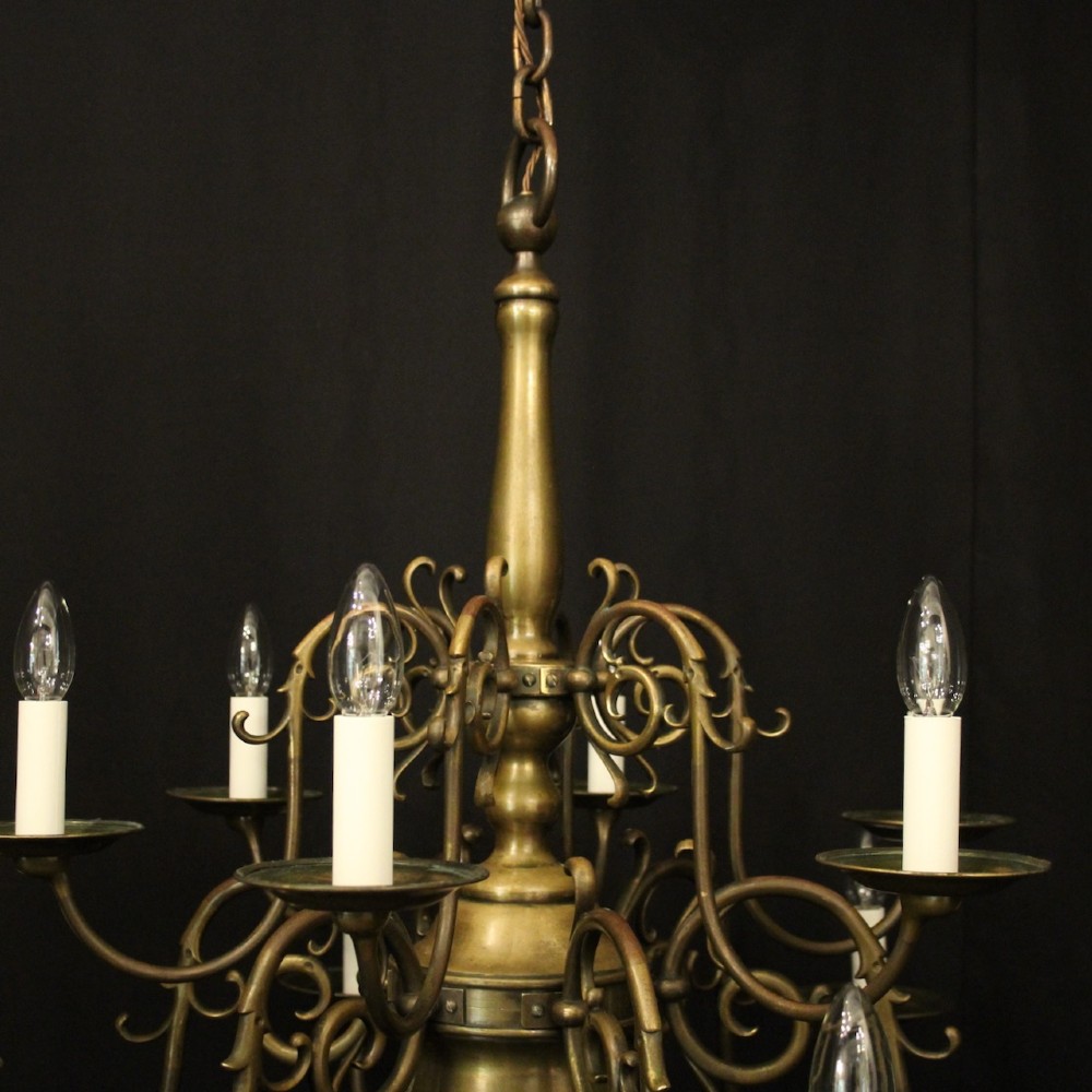 An antique English twelve-light bronze chandelier featuring scrollwork arms, candle sleeves, drip pans, and a turned central stem. View VIII