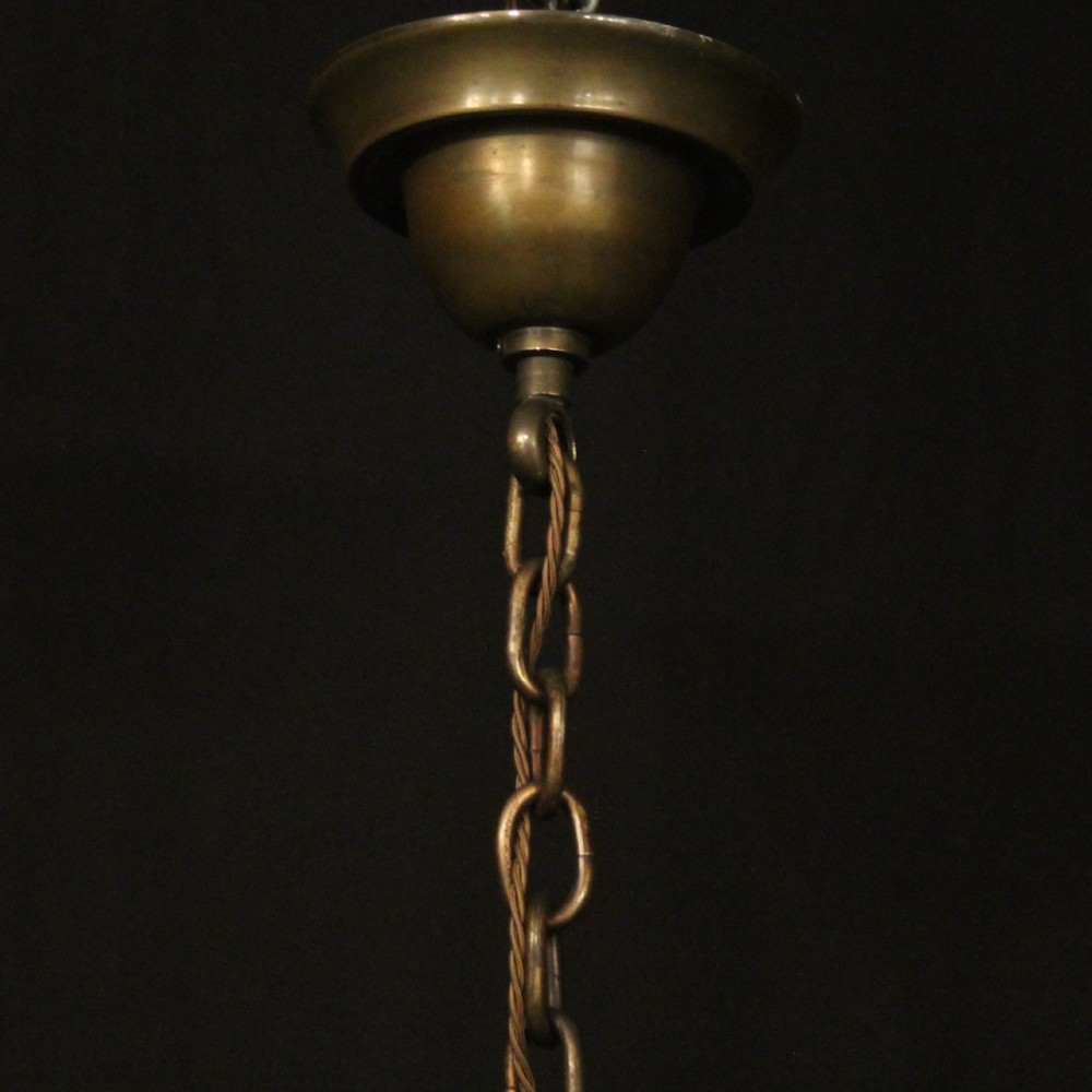 An antique English twelve-light bronze chandelier featuring scrollwork arms, candle sleeves, drip pans, and a turned central stem. View X