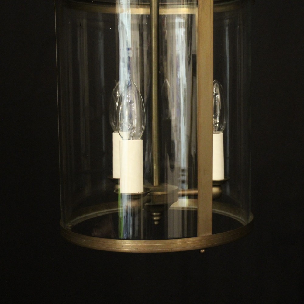 A cylindrical gilt brass hall lantern featuring curved clear glass panels, a central three-light candle fixture, and a suspended hanging chain. View IV