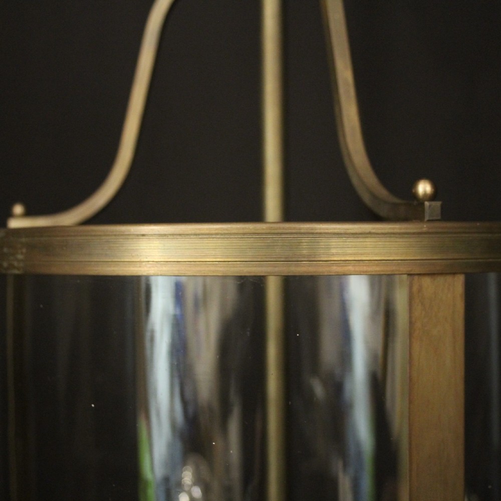 A cylindrical gilt brass hall lantern featuring curved clear glass panels, a central three-light candle fixture, and a suspended hanging chain. View VII