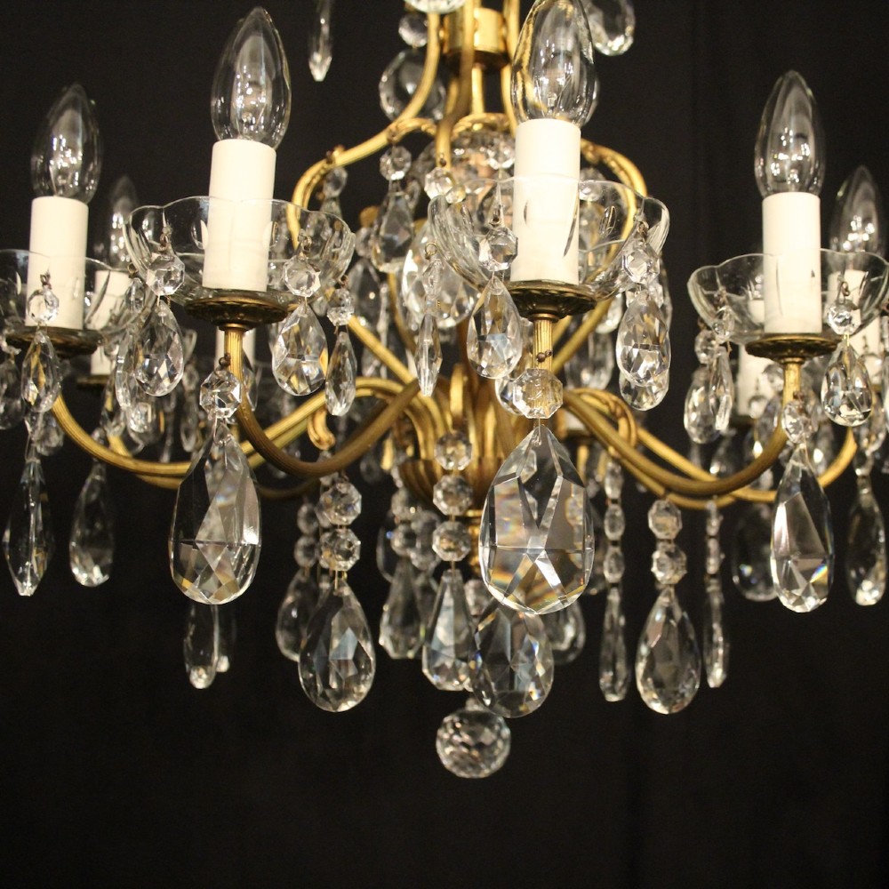 A nine-light French gilded metal chandelier featuring curved scroll arms, white candle sleeves, and suspended clear glass droplet pendants. View III