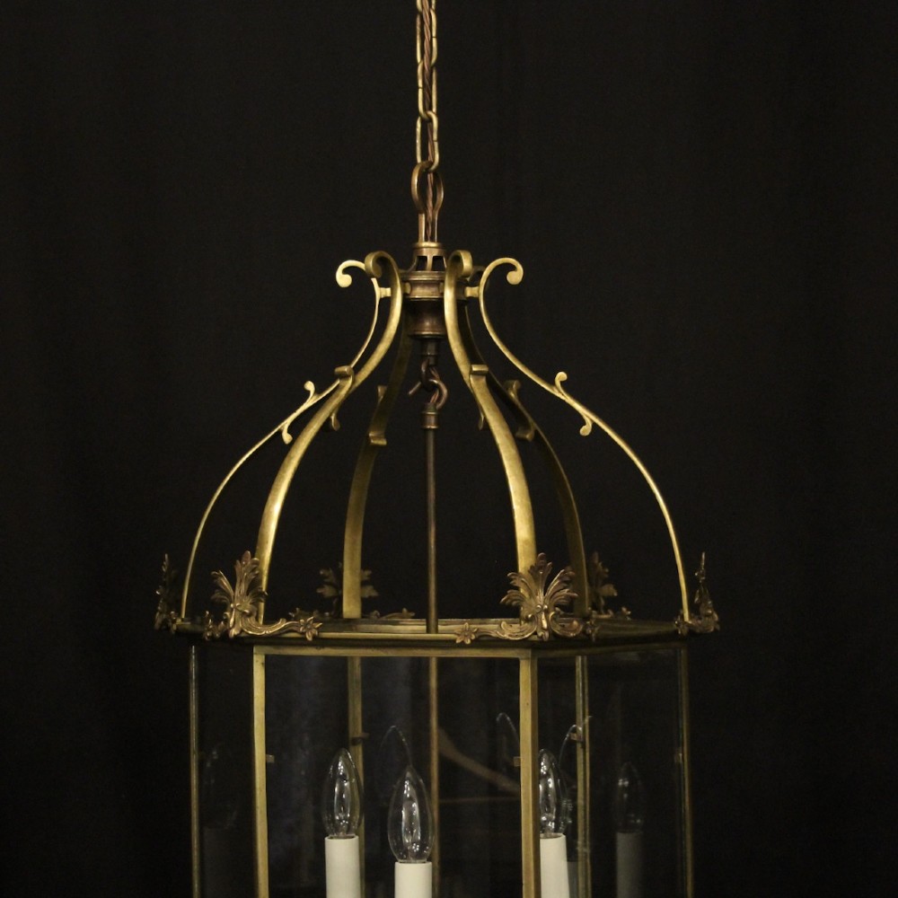 A pair of antique brass hexagonal hall lanterns with glazed glass panels and triple candle-style light fittings suspended from chains. View III