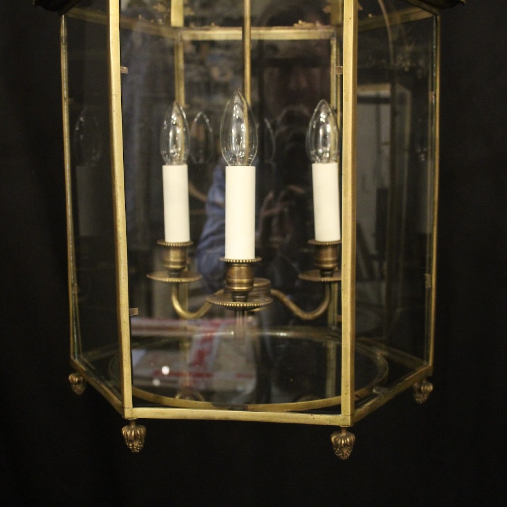 A pair of antique brass hexagonal hall lanterns with glazed glass panels and triple candle-style light fittings suspended from chains. View IV