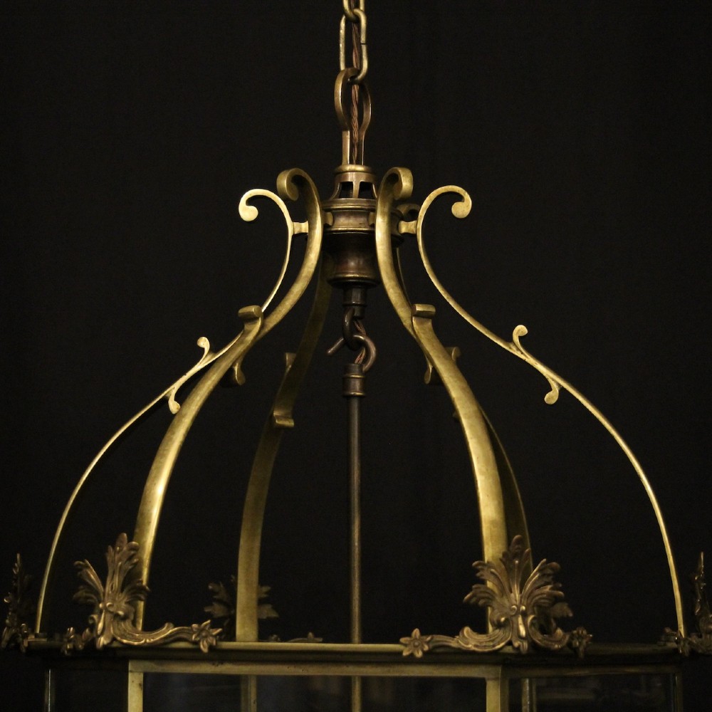 A pair of antique brass hexagonal hall lanterns with glazed glass panels and triple candle-style light fittings suspended from chains. View V