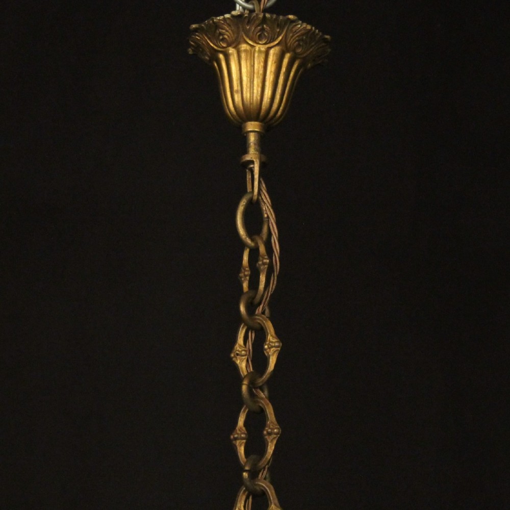 A multi-tiered antique French ceiling chandelier made of gilded brass with sixteen candle-style lights and faceted crystal drops against a dark background. View X