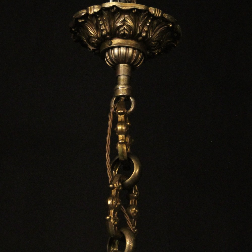An antique French eight-light chandelier crafted from gilded bronze, featuring sculpted figures, classical motifs, and candle-style bulb holders. View X