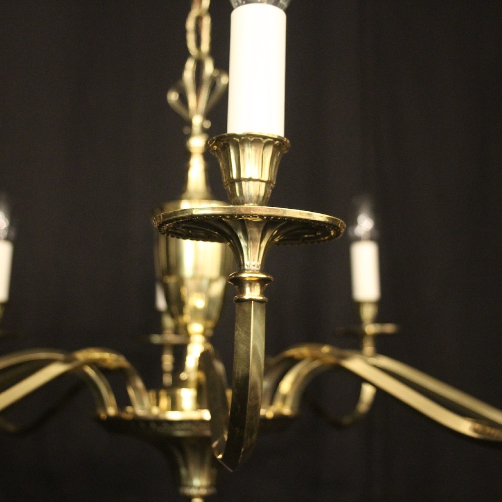 A repolished brass ten-light chandelier featuring sweeping curved arms, candle sleeves, and a central urn-shaped stem hanging from a chain. View V