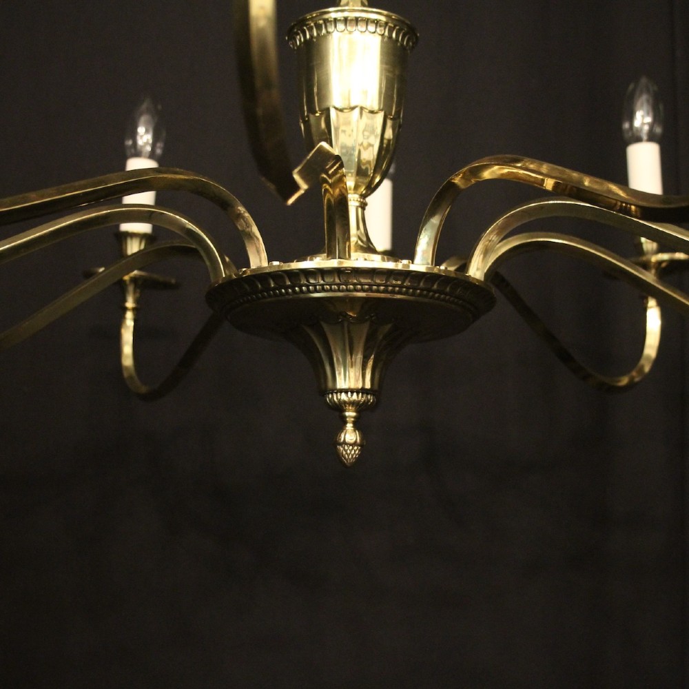 A repolished brass ten-light chandelier featuring sweeping curved arms, candle sleeves, and a central urn-shaped stem hanging from a chain. View VII