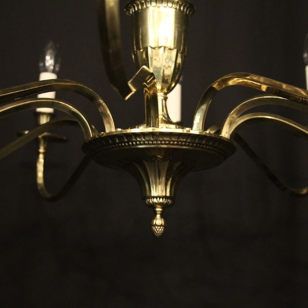 A repolished brass ten-light chandelier featuring sweeping curved arms, candle sleeves, and a central urn-shaped stem hanging from a chain. View VIII