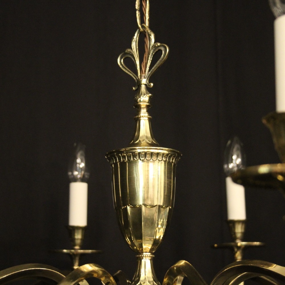 A repolished brass ten-light chandelier featuring sweeping curved arms, candle sleeves, and a central urn-shaped stem hanging from a chain. View IX