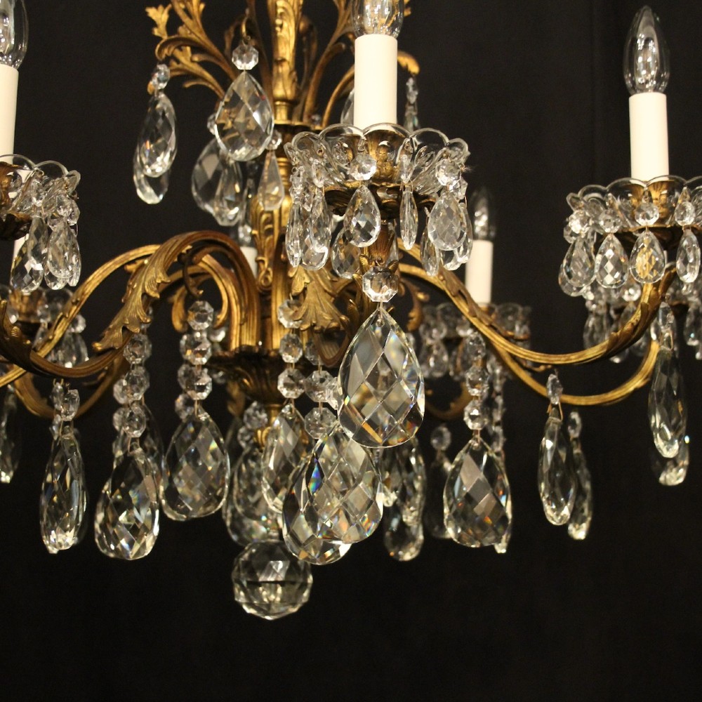 An eight-light French chandelier featuring a gilded metal frame adorned with cut crystal teardrop pendants and glass candle sleeves. View III