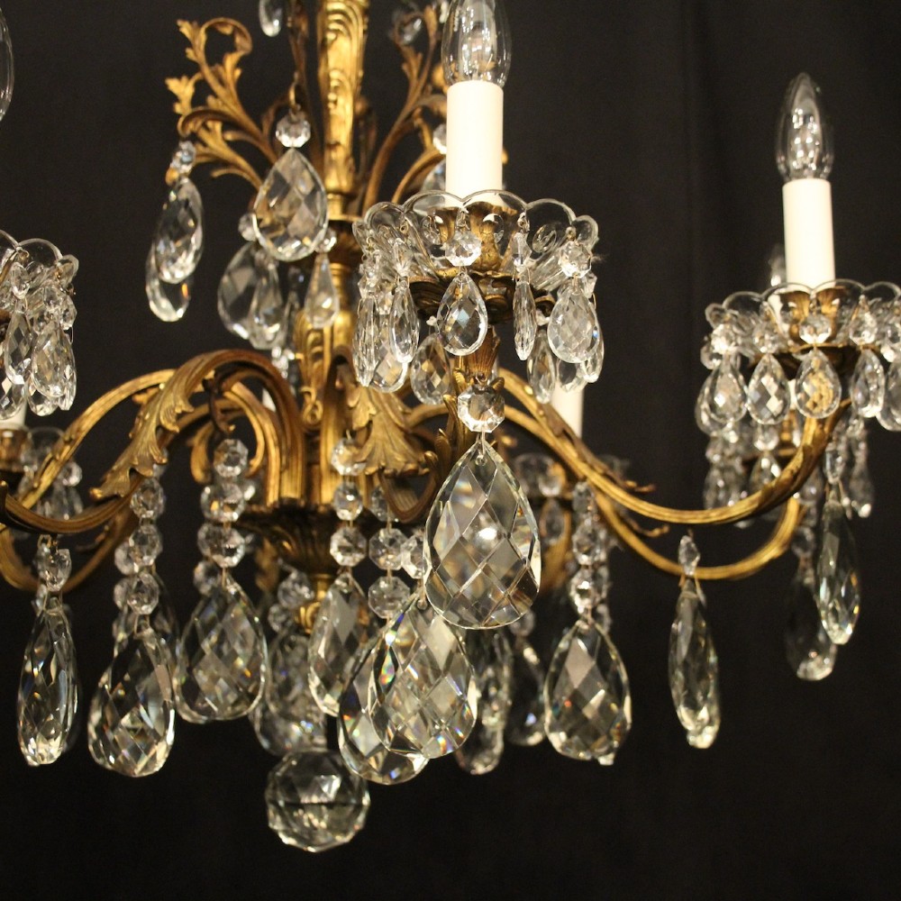 An eight-light French chandelier featuring a gilded metal frame adorned with cut crystal teardrop pendants and glass candle sleeves. View IV
