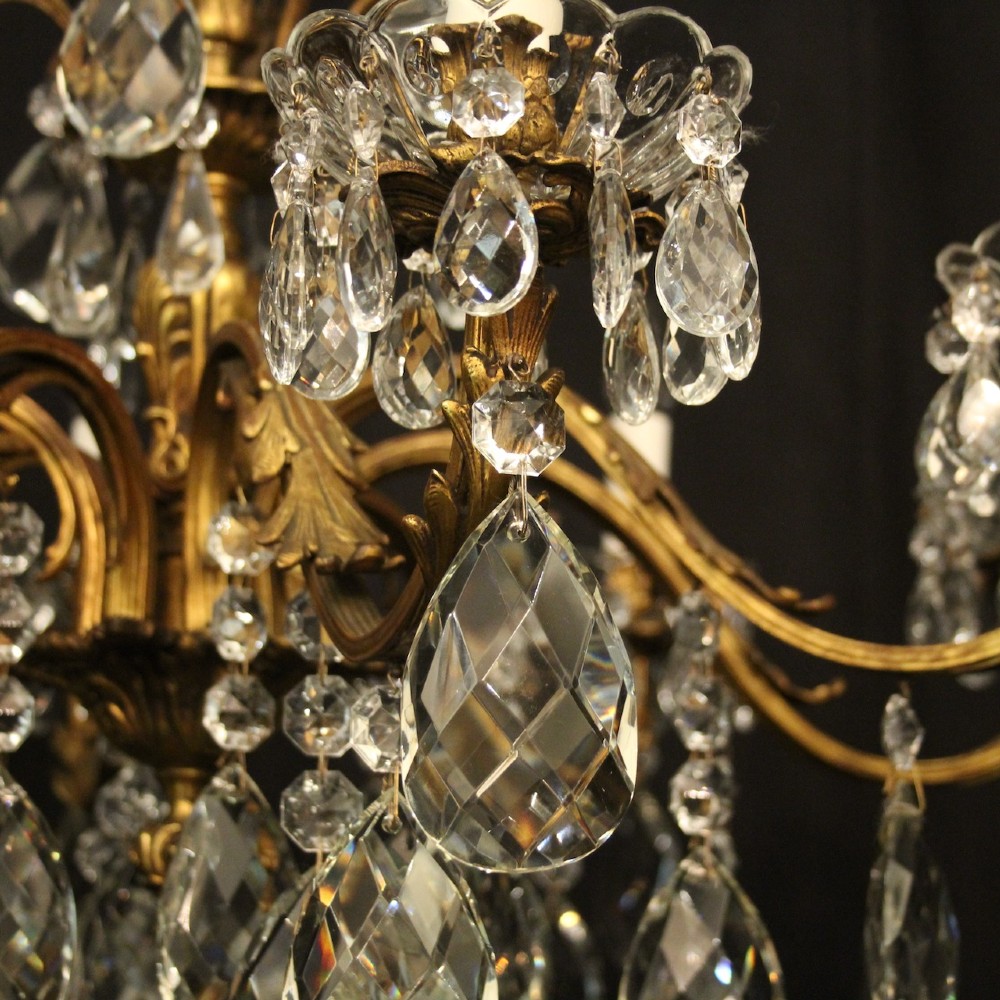 An eight-light French chandelier featuring a gilded metal frame adorned with cut crystal teardrop pendants and glass candle sleeves. View V