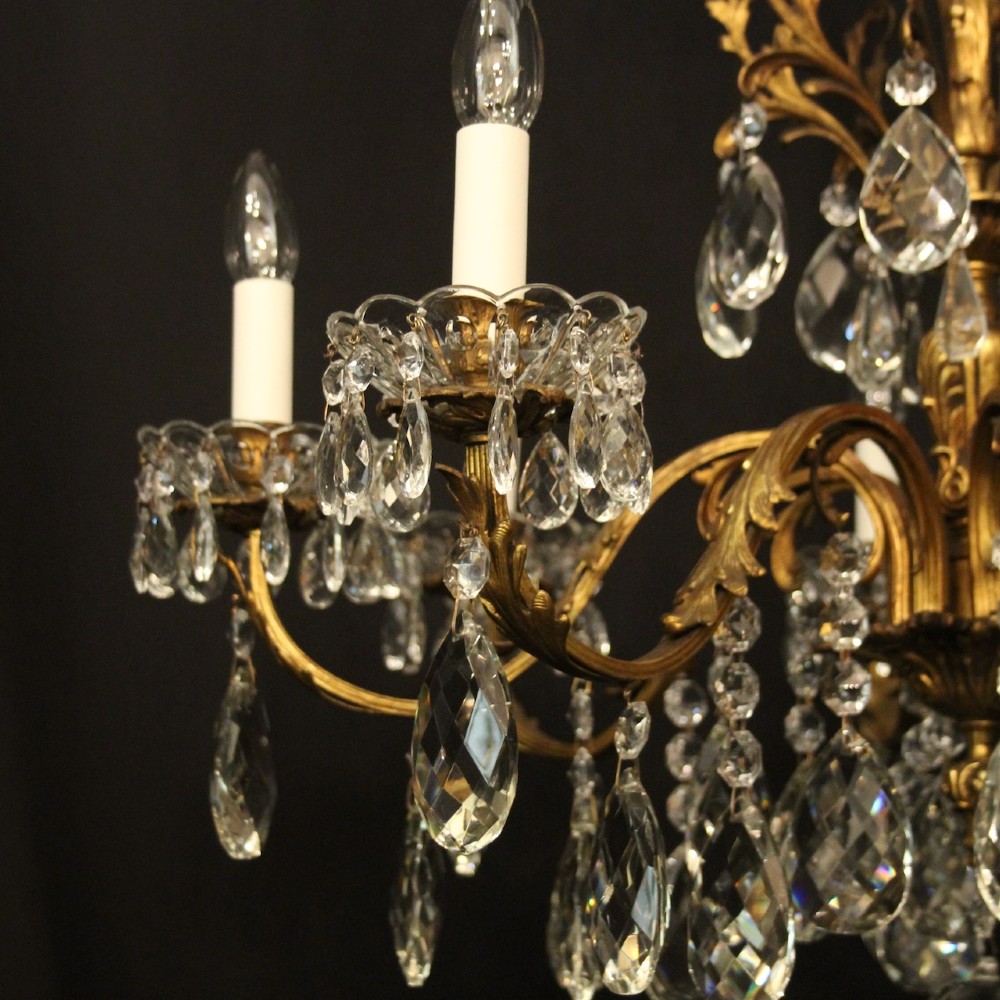 An eight-light French chandelier featuring a gilded metal frame adorned with cut crystal teardrop pendants and glass candle sleeves. View VI