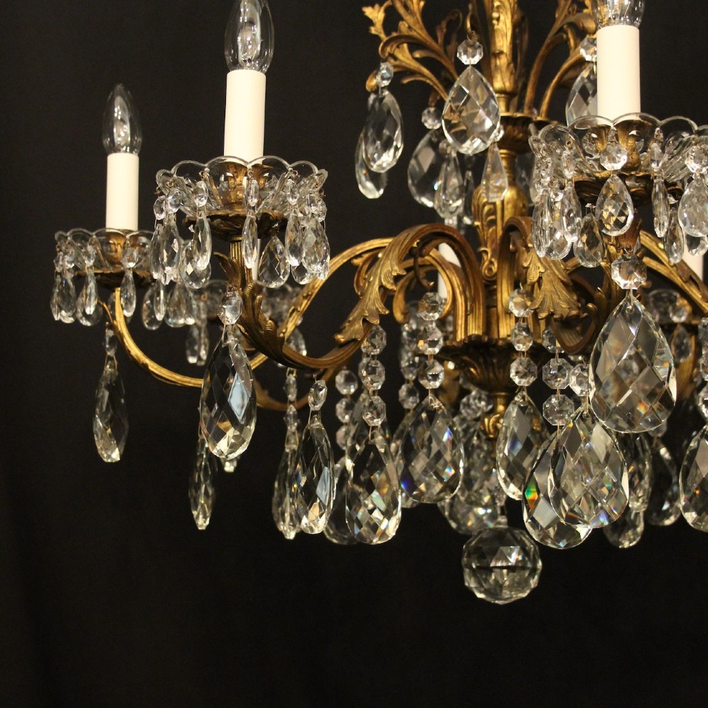 An eight-light French chandelier featuring a gilded metal frame adorned with cut crystal teardrop pendants and glass candle sleeves. View VII