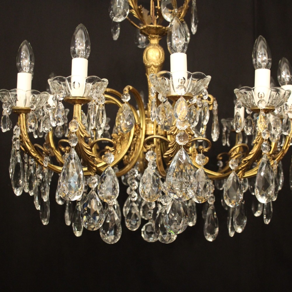 A French gilded brass twelve-light chandelier hung with faceted crystal droplets and glass bobeches. View VII