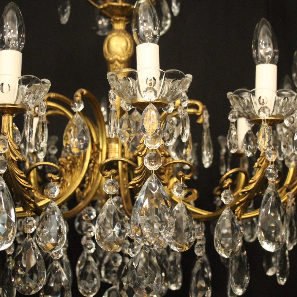 A French gilded brass twelve-light chandelier hung with faceted crystal droplets and glass bobeches. View VIII