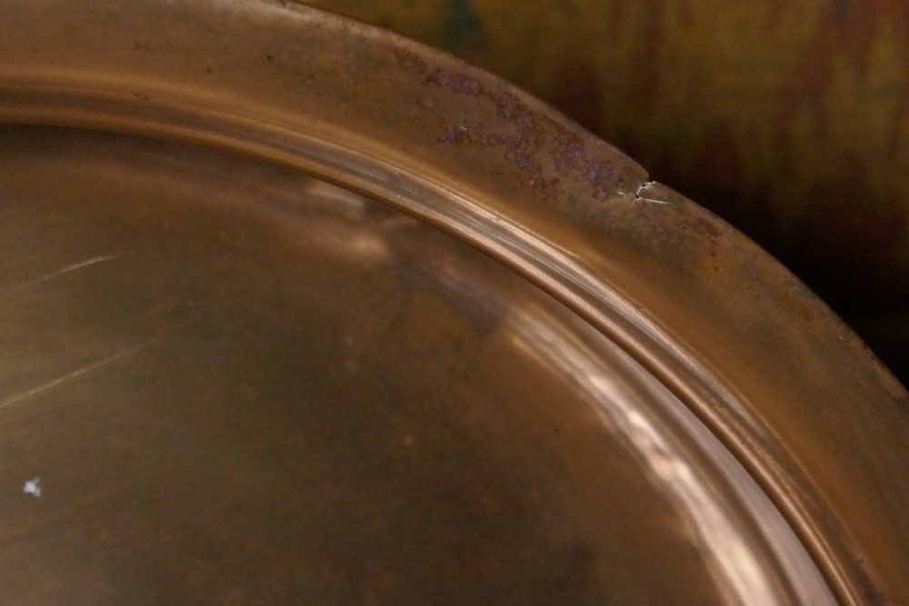 A circular 16th century bronze bowl featuring a broad flat rim and a raised central boss. View V