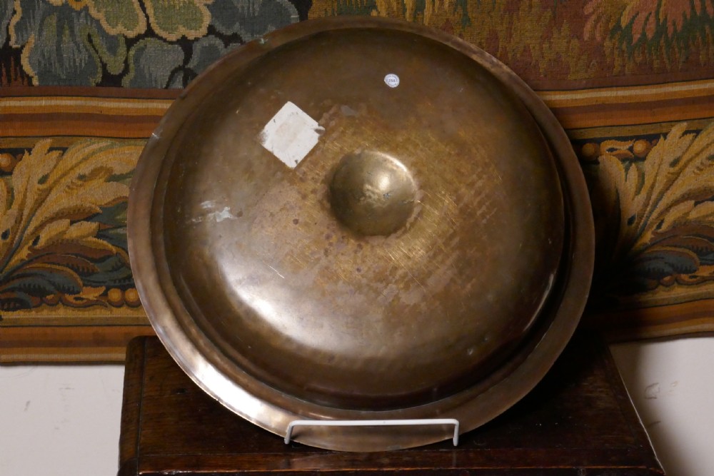 A circular 16th century bronze bowl featuring a broad flat rim and a raised central boss. View VI