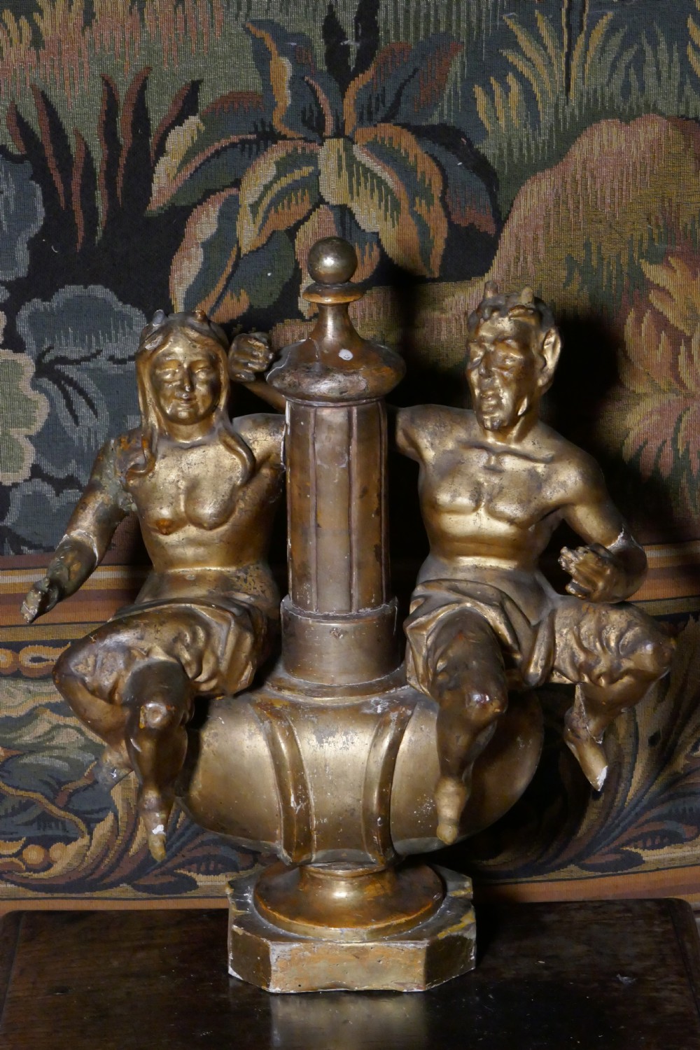 An 18th-century gilded carving featuring a central fluted column flanked by two seated mythological figures on an octagonal base.