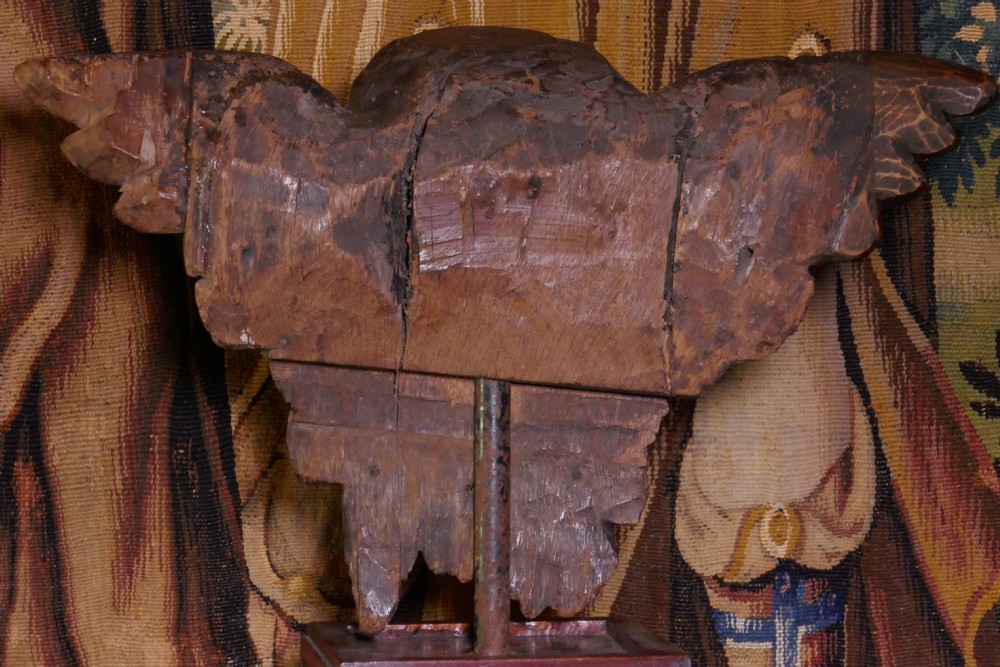 A dark carved oak winged cherub head with detailed feathering and curled hair, mounted upon a wooden square plinth base. View IV