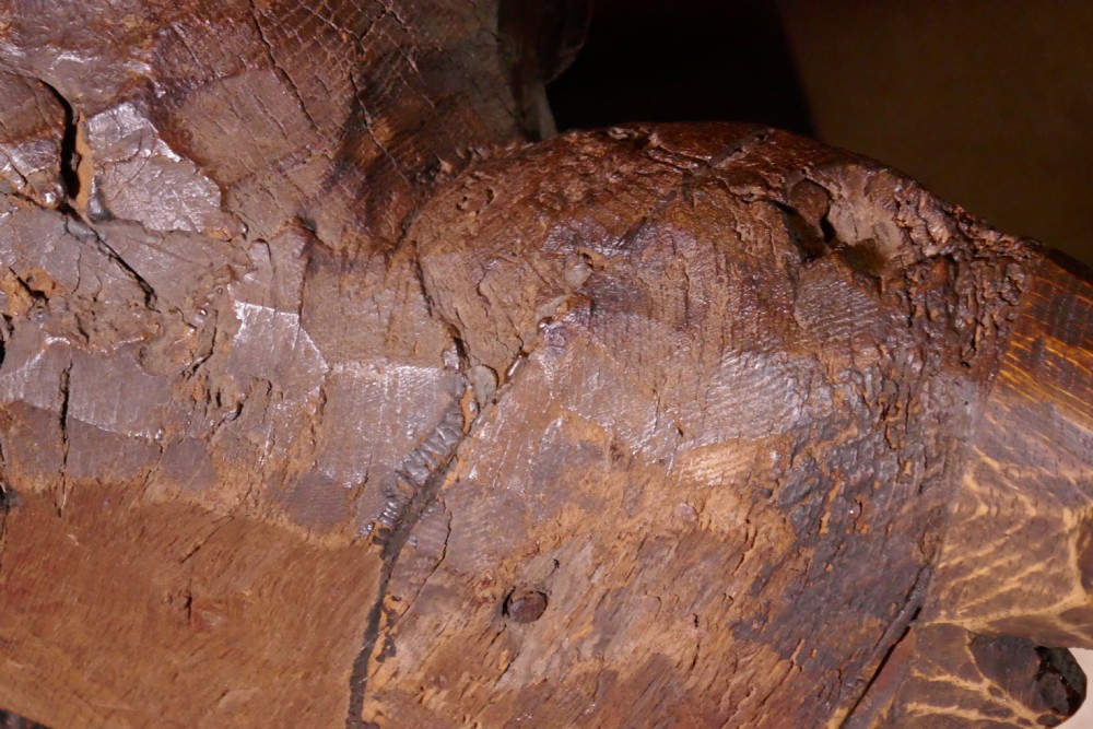 A dark carved oak winged cherub head with detailed feathering and curled hair, mounted upon a wooden square plinth base. View VIII