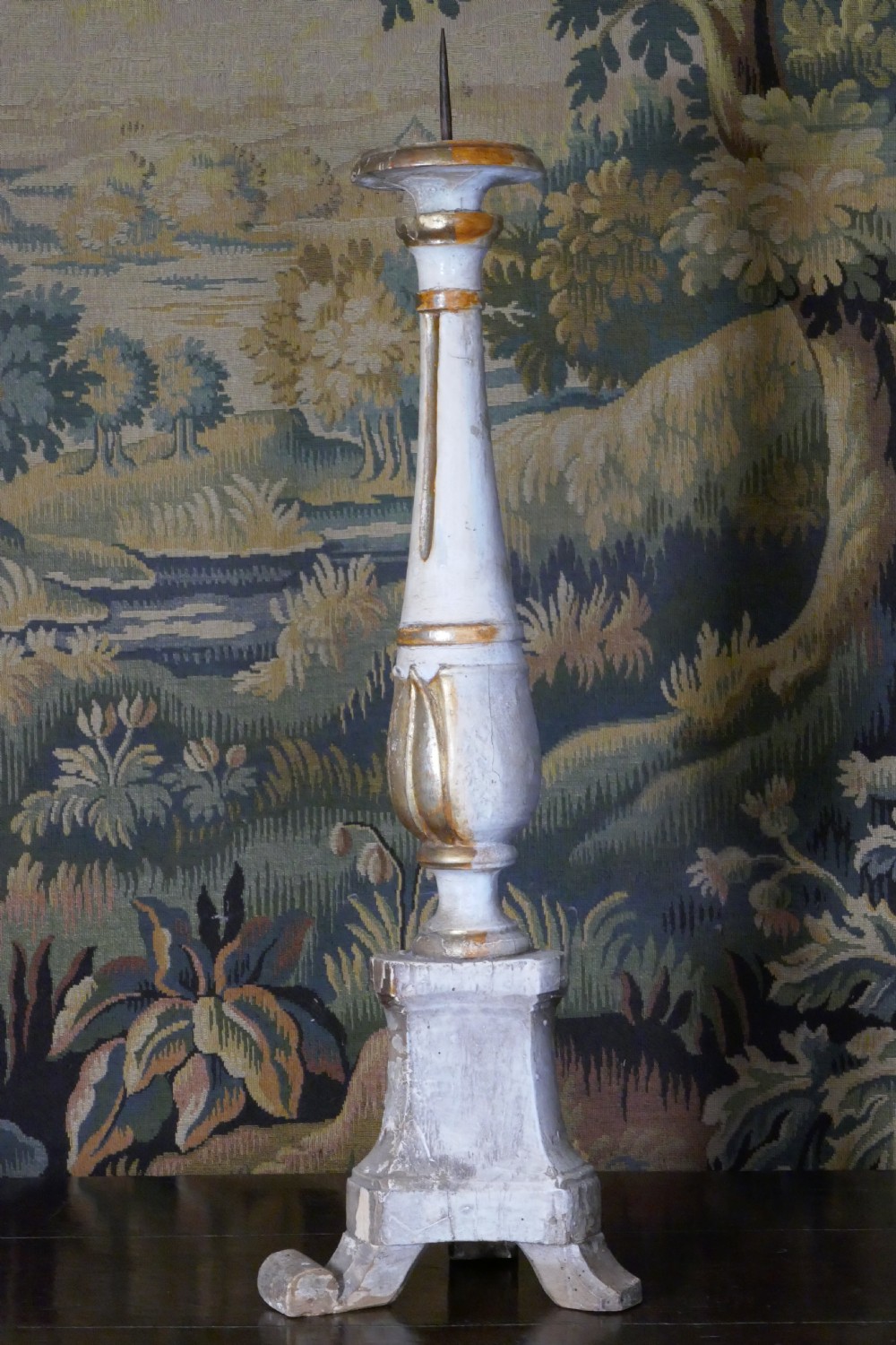 A carved 19th-century wooden pricket candlestick featuring distressed off-white paint, exposed gold leafing, an acanthus column motif, and an iron candle spike. View IV