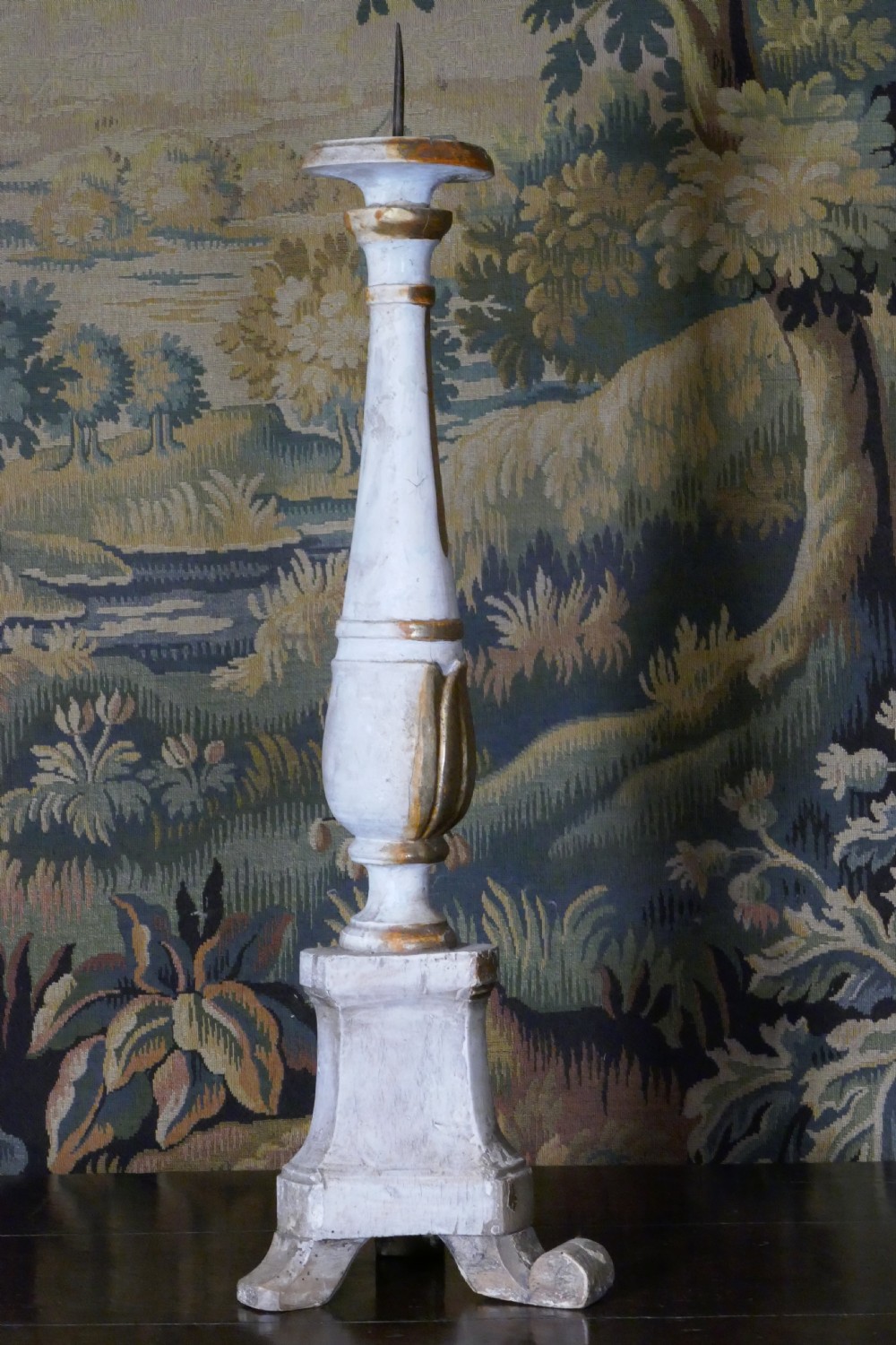 A carved 19th-century wooden pricket candlestick featuring distressed off-white paint, exposed gold leafing, an acanthus column motif, and an iron candle spike. View VII
