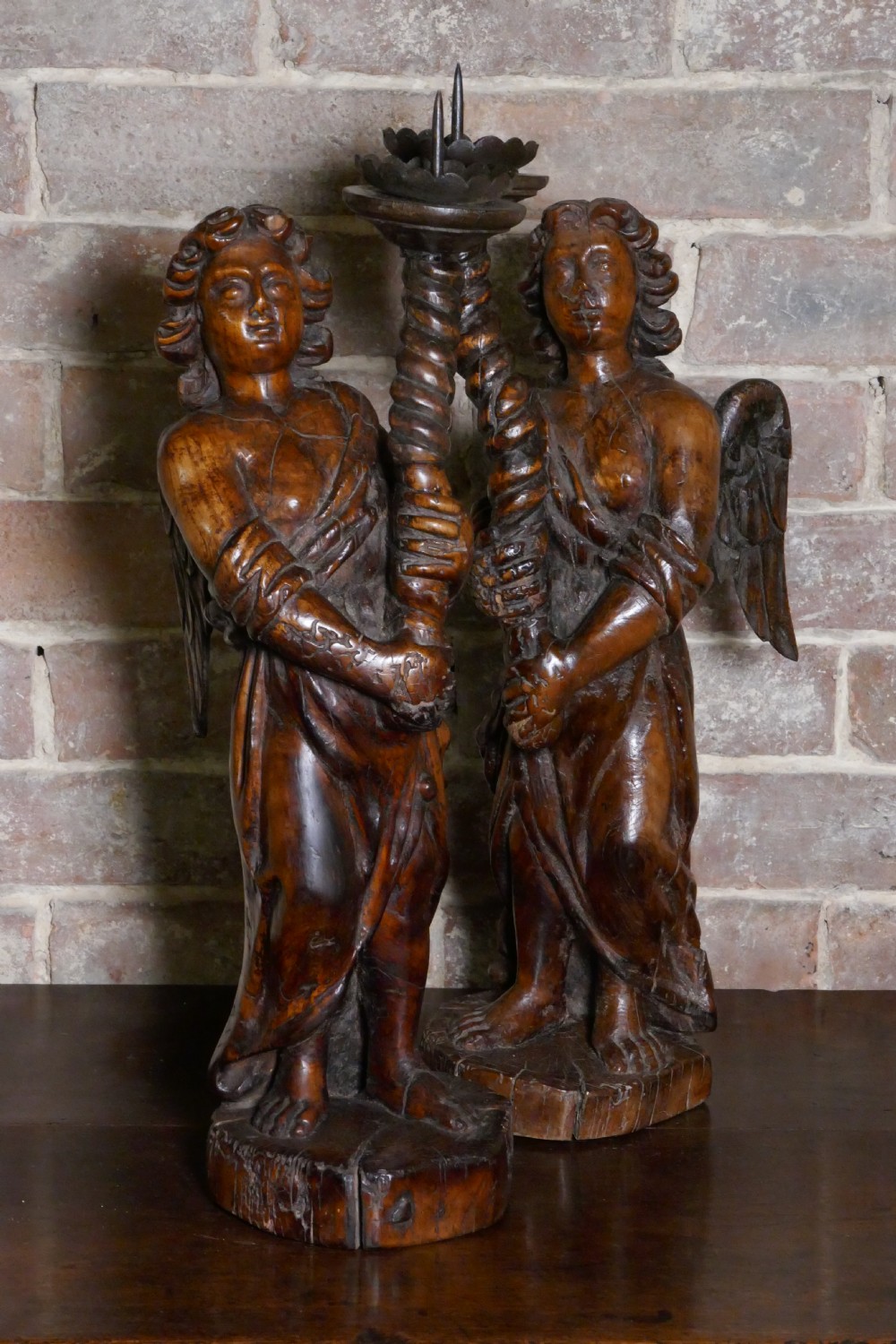 A pair of antique hand-carved wooden candlesticks depicting standing winged angels holding barley-twist pricket stands. View II