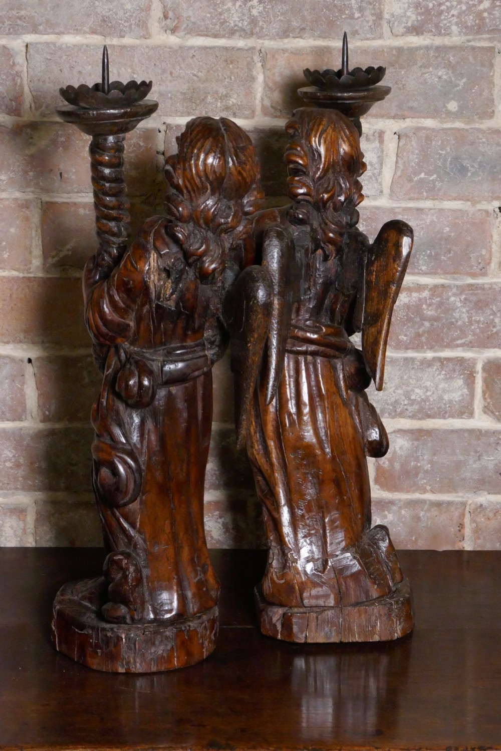 A pair of antique hand-carved wooden candlesticks depicting standing winged angels holding barley-twist pricket stands. View III