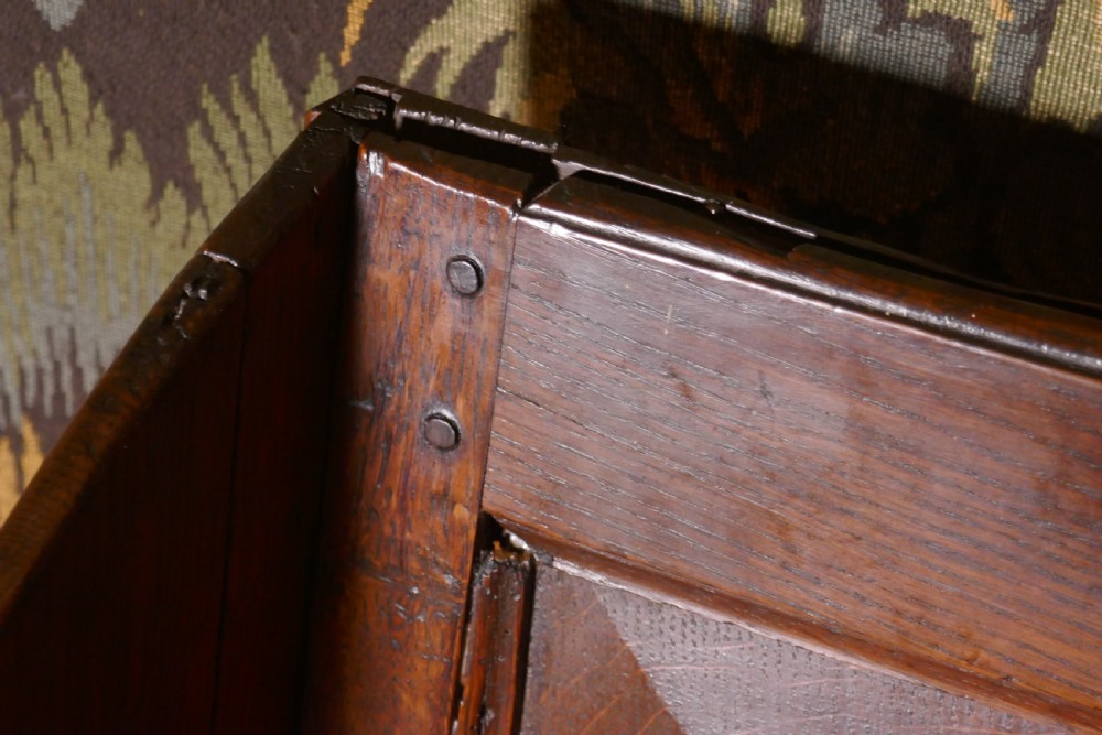 A solid dark oak Georgian wing back armchair featuring a fielded panel back, shaped armrests, and turned front legs connected by stretchers. View XII