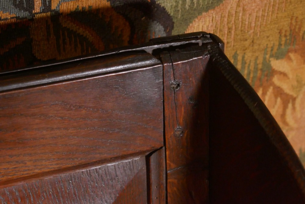 A solid dark oak Georgian wing back armchair featuring a fielded panel back, shaped armrests, and turned front legs connected by stretchers. View XIII