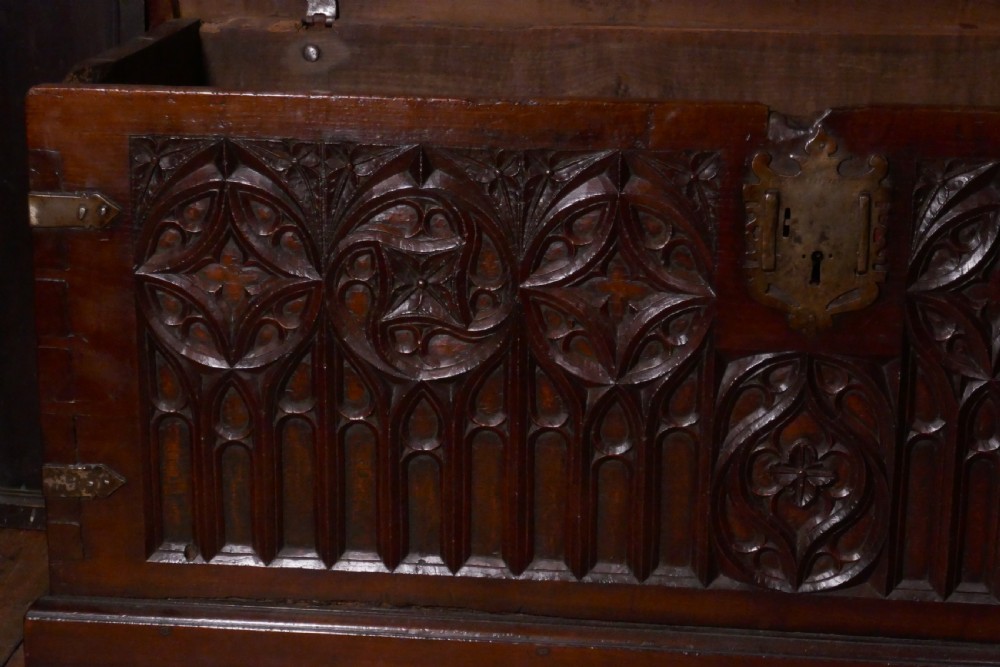 A dark oak 16th-century coffer featuring carved Gothic tracery panels and a central iron lock mechanism. View III