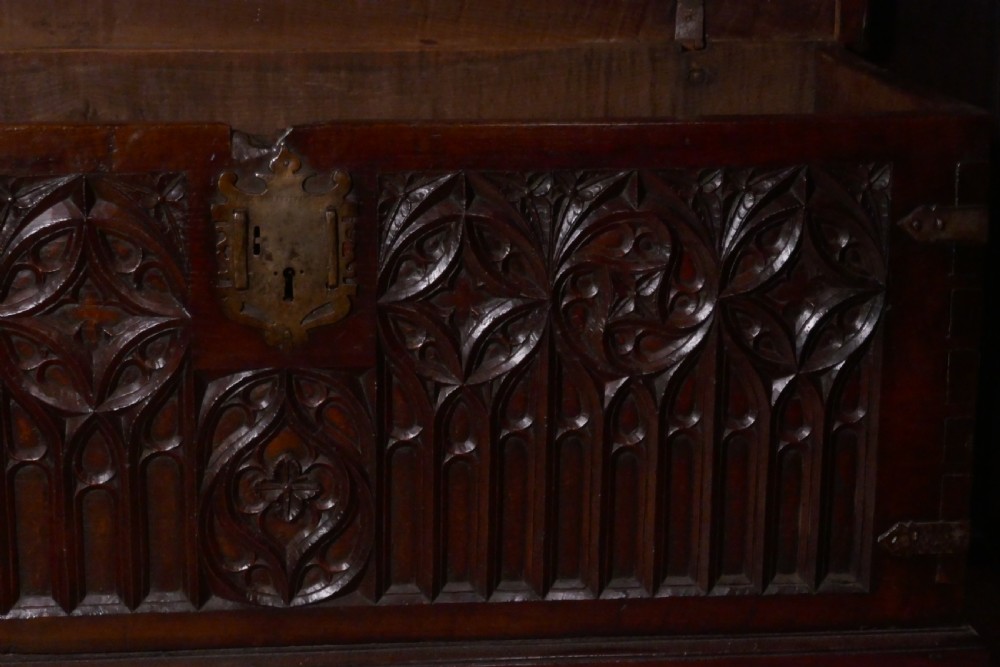 A dark oak 16th-century coffer featuring carved Gothic tracery panels and a central iron lock mechanism. View IV